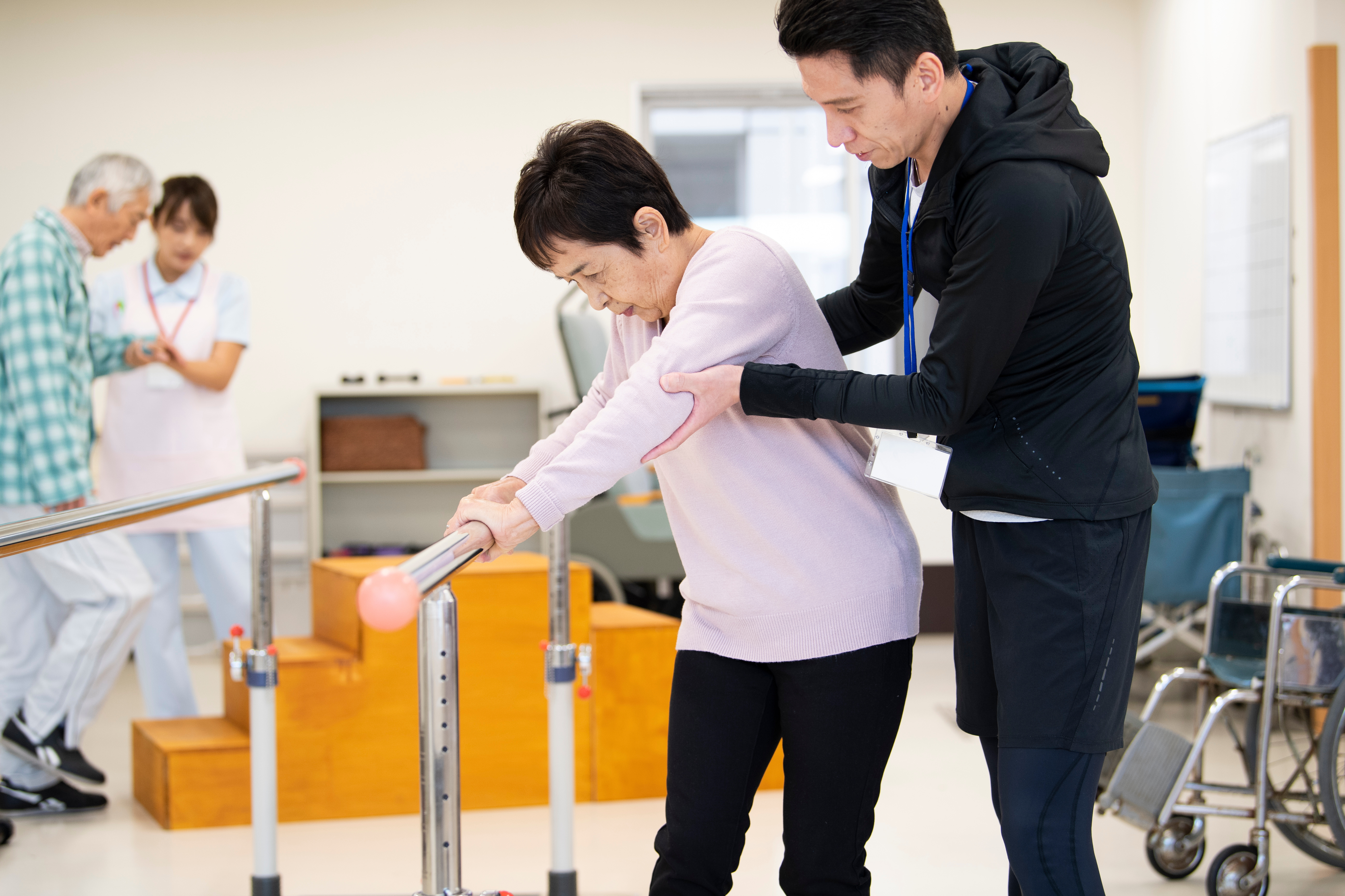 高齢女性の歩行訓練を補助する男性理学療法士